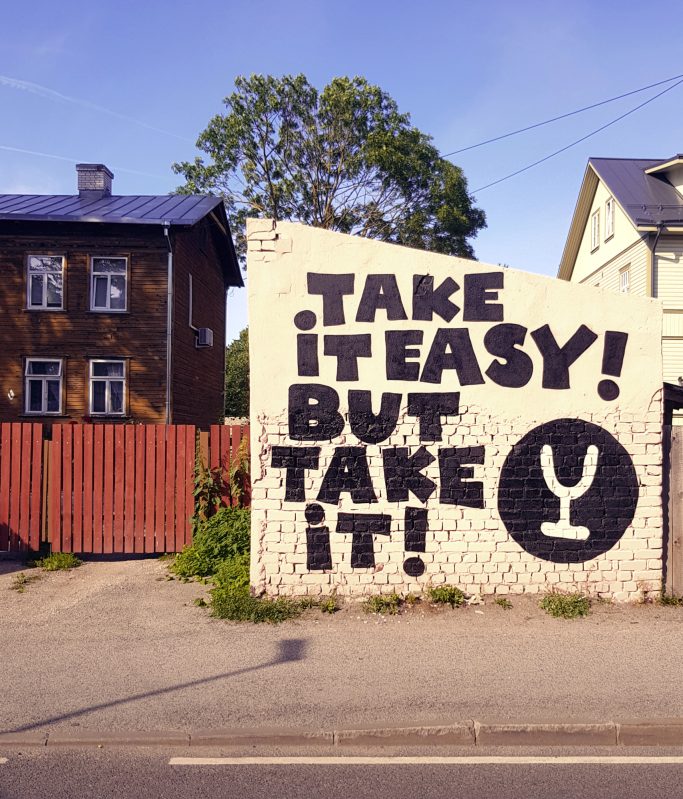 Wandbild mit dem Text: „Take it easy! But take it!“ und einem Glas-Symbol.